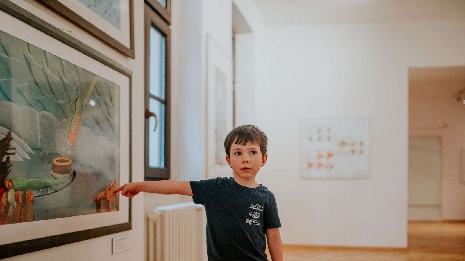Un niño señala un cuadro en una sala de exposiciones de arte