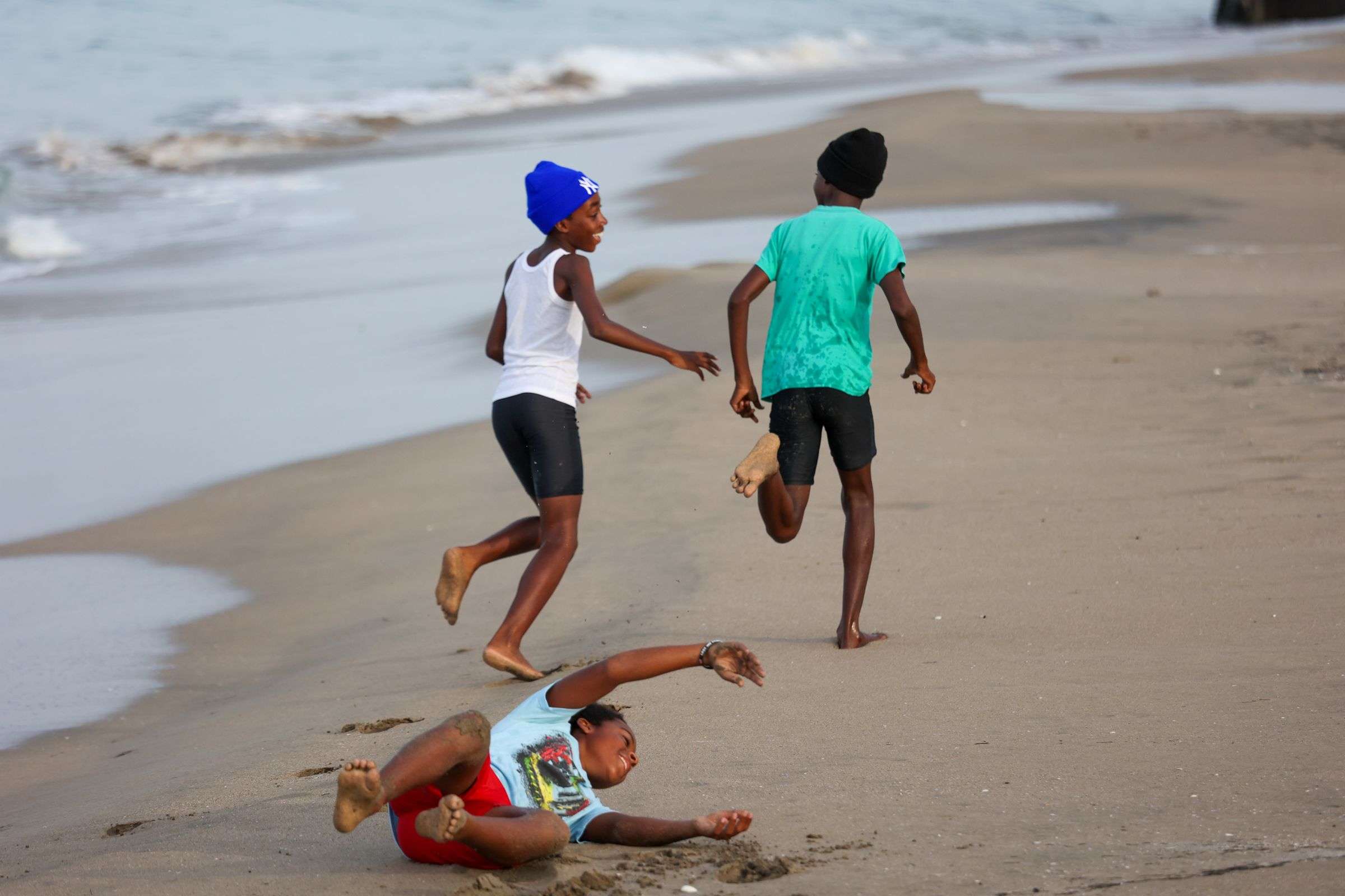 Tres niños corren y juegan en la arena de una playa del Caribe